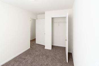 an empty bedroom with white walls and carpet and a closet
